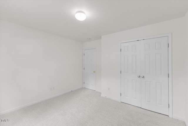 unfurnished bedroom featuring light carpet, a closet, and baseboards