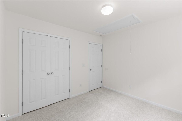 unfurnished bedroom with attic access, carpet flooring, baseboards, and a closet