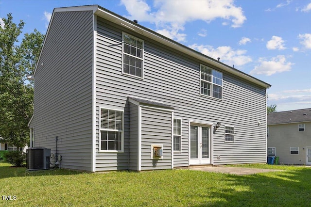 back of house featuring central air condition unit and a lawn