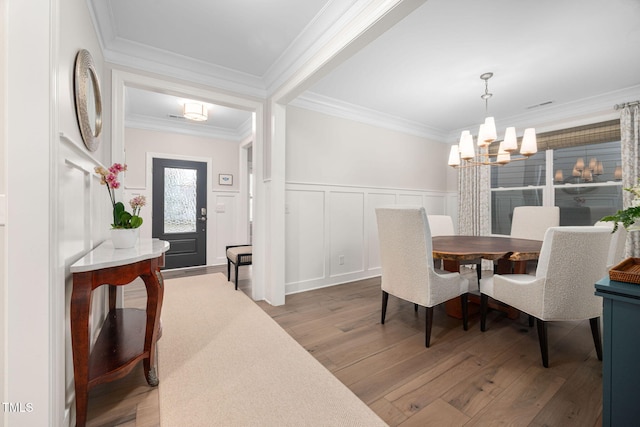829 Churton Pl, Cary, NC 27518 - dining room featuring light wood finished floors, a chandelier, crown molding, a wainscoted wall, and a decorative wall