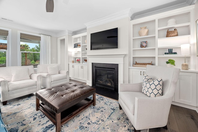 829 Churton Pl, Cary, NC 27518 - living area featuring crown molding, a ceiling fan, a glass covered fireplace, wood finished floors, and built in shelves