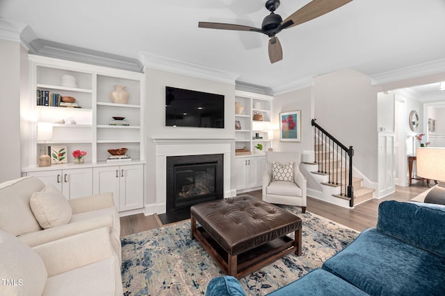 829 Churton Pl, Cary, NC 27518 - living room featuring crown molding, wood finished floors, ceiling fan, stairs, and a glass covered fireplace