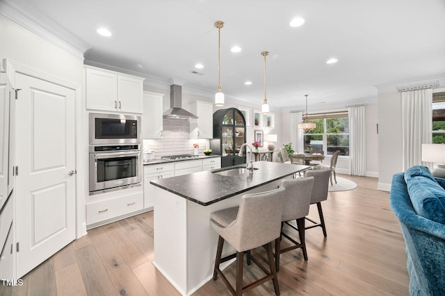 829 Churton Pl, Cary, NC 27518 - kitchen featuring stainless steel appliances, a sink, wall chimney exhaust hood, crown molding, and a kitchen bar