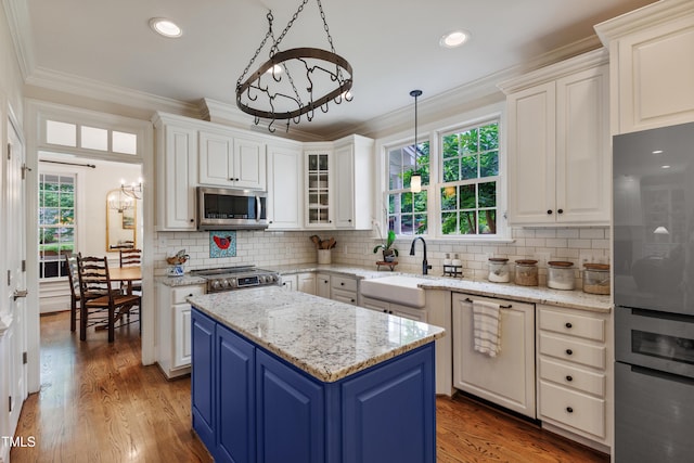 200 Cobblepoint Way, Holly Springs, NC 27540 - kitchen with appliances with stainless steel finishes, blue cabinetry, white cabinets, a center island, and ornamental molding