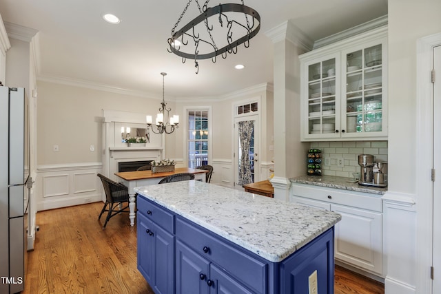 200 Cobblepoint Way, Holly Springs, NC 27540 - kitchen with a chandelier, blue cabinets, freestanding refrigerator, wood finished floors, and ornamental molding