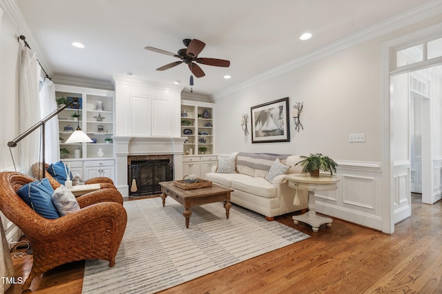 200 Cobblepoint Way, Holly Springs, NC 27540 - living area featuring light wood-type flooring, a ceiling fan, a fireplace, a wainscoted wall, and ornamental molding