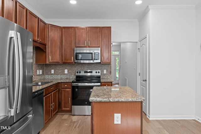 3204 Plaza Pl, Raleigh, NC 27612 - kitchen featuring appliances with stainless steel finishes, a center island, light wood finished floors, light stone countertops, and backsplash