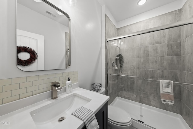 bathroom featuring a shower stall, toilet, vanity, and tasteful backsplash