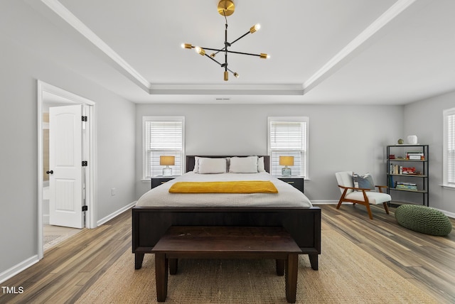bedroom with a raised ceiling, a chandelier, wood finished floors, and baseboards