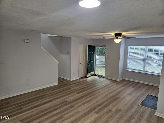 unfurnished living room with a textured ceiling, wood finished floors, baseboards, and a ceiling fan