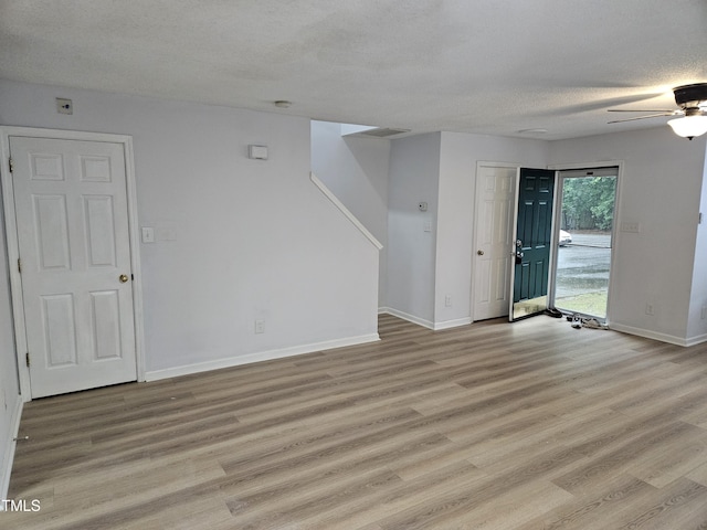 unfurnished living room with a textured ceiling, light wood-type flooring, baseboards, and a ceiling fan