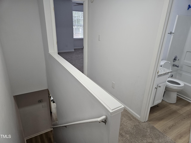 stairs with carpet flooring, baseboards, and wood finished floors