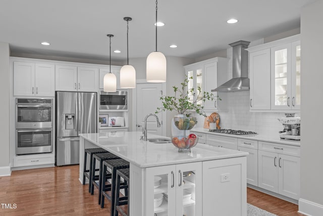 2711 Jordan Pointe Blvd, New Hill, NC 27562 - kitchen featuring appliances with stainless steel finishes, a sink, wall chimney range hood, backsplash, and an island with sink