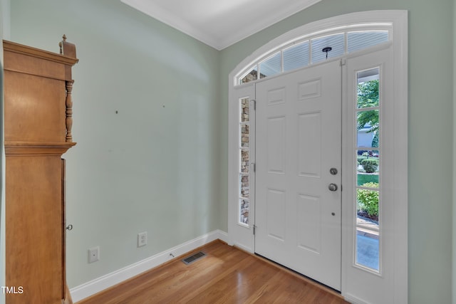 entrance foyer featuring light wood-style floors, crown molding, and baseboards