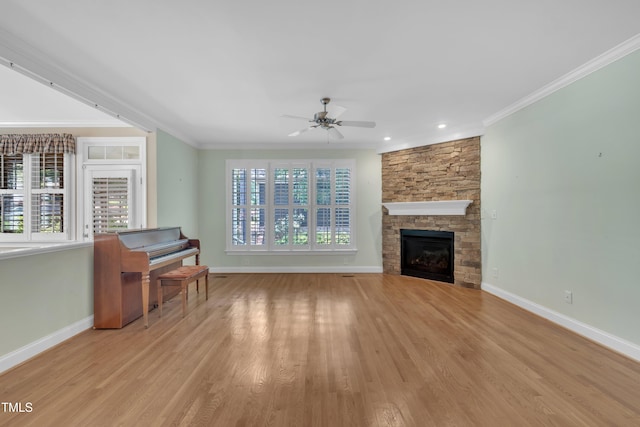 unfurnished living room featuring a ceiling fan, baseboards, crown molding, light wood-style floors, and a fireplace
