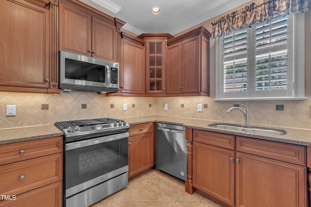 kitchen with stainless steel appliances, a sink, stone counters, brown cabinets, and recessed lighting