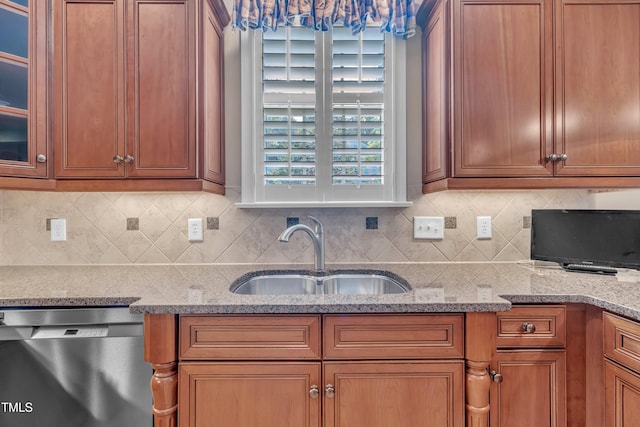 kitchen featuring stainless steel dishwasher, a sink, tasteful backsplash, brown cabinetry, and glass insert cabinets