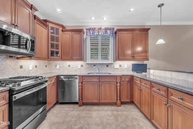 kitchen with stainless steel appliances, a sink, brown cabinets, dark stone countertops, and crown molding