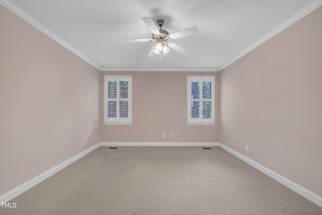 empty room featuring healthy amount of natural light, baseboards, a ceiling fan, light colored carpet, and ornamental molding