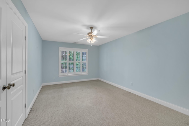 unfurnished room with a ceiling fan, baseboards, and light carpet