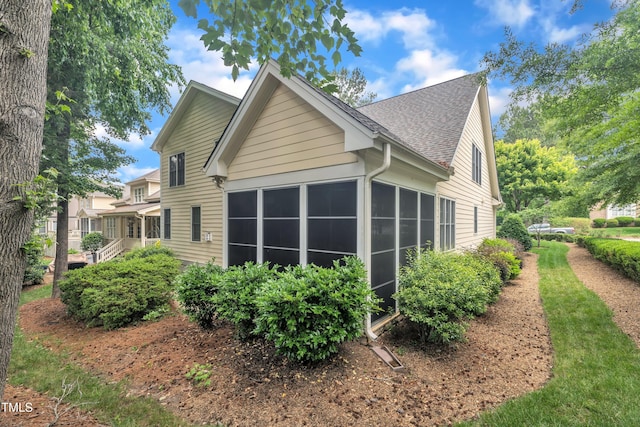 view of home's exterior featuring a sunroom and a shingled roof