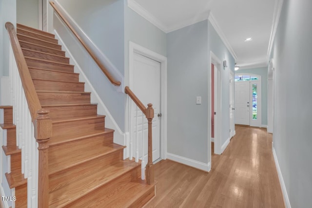 stairs with wood finished floors, ornamental molding, baseboards, and recessed lighting