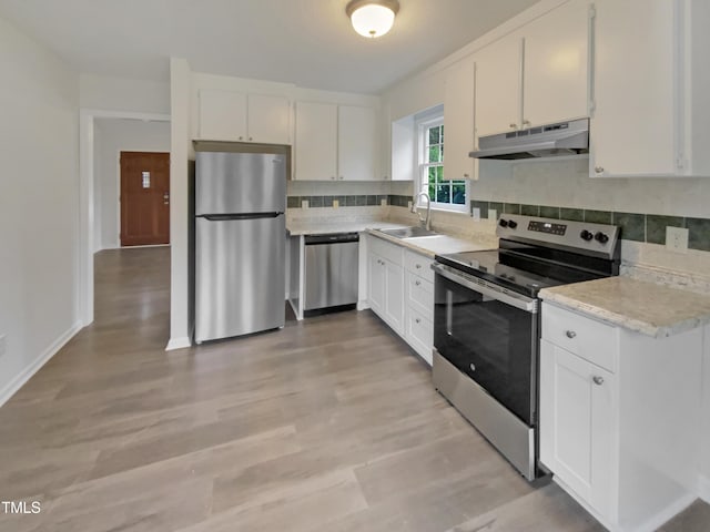 kitchen featuring appliances with stainless steel finishes, under cabinet range hood, a sink, white cabinets, and tasteful backsplash