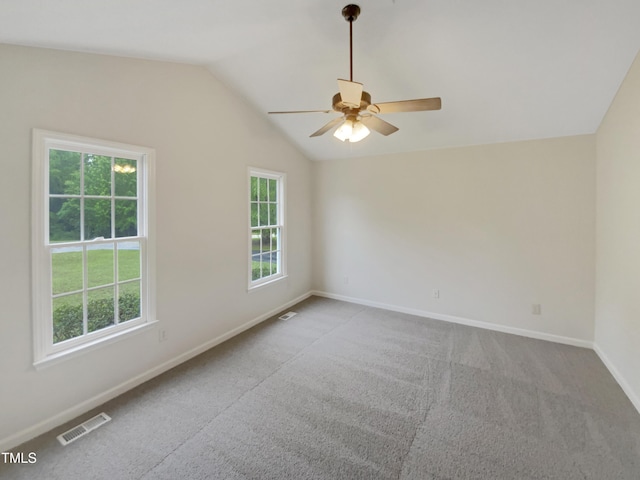 spare room with plenty of natural light, vaulted ceiling, a ceiling fan, baseboards, and carpet flooring