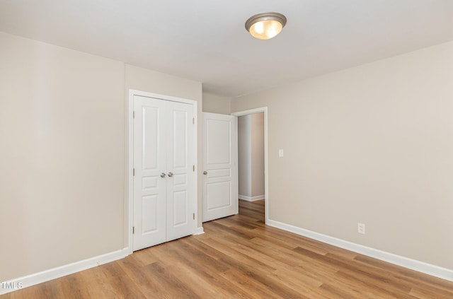 unfurnished bedroom with baseboards, light wood-type flooring, and a closet