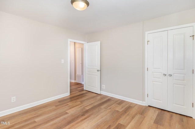 unfurnished bedroom with light wood-style floors, baseboards, and a closet