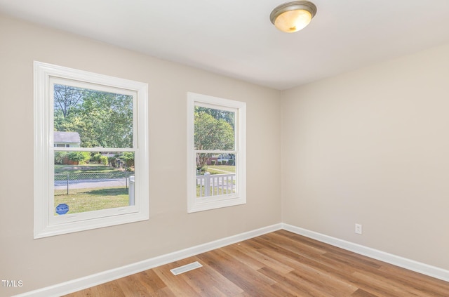 unfurnished room with baseboards, plenty of natural light, and wood finished floors