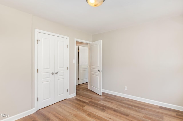 unfurnished bedroom with light wood finished floors, baseboards, and a closet