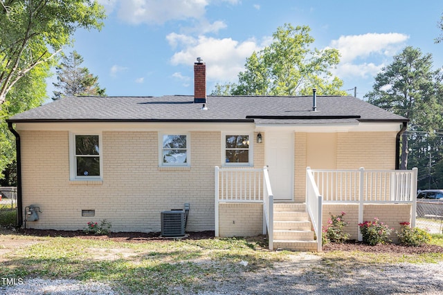 rear view of property with brick siding, central air condition unit, crawl space, and a chimney