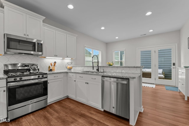 8925 Lee Brown Ridge Dr, Wake Forest, NC 27587 - kitchen featuring appliances with stainless steel finishes, a sink, a peninsula, white cabinetry, and backsplash