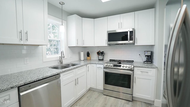 4613 Nesbit Ct, Raleigh, NC 27616 - kitchen featuring stainless steel appliances, a sink, white cabinets, light wood-style floors, and decorative backsplash
