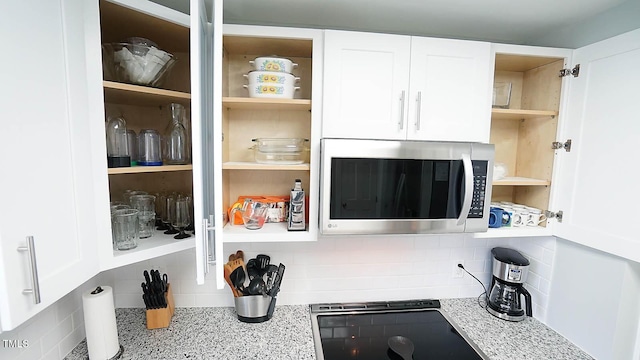 4613 Nesbit Ct, Raleigh, NC 27616 - kitchen view of open shelves, stainless steel microwave, white cabinetry, light stone countertops, and decorative backsplash