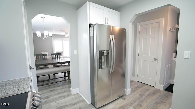 4613 Nesbit Ct, Raleigh, NC 27616 - kitchen featuring stainless steel fridge, light wood-style floors, arched walkways, and white cabinetry