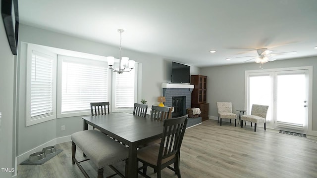 4613 Nesbit Ct, Raleigh, NC 27616 - dining room with a chandelier, a brick fireplace, baseboards, light wood finished floors, and a ceiling fan