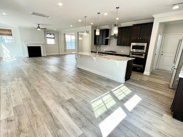 8813 Moss Glen Dr, Raleigh, NC 27617 - kitchen with stainless steel appliances, wall chimney exhaust hood, ornamental molding, ceiling fan, and a breakfast bar