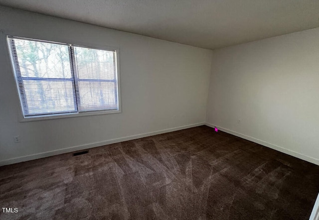 unfurnished room with dark carpet and baseboards