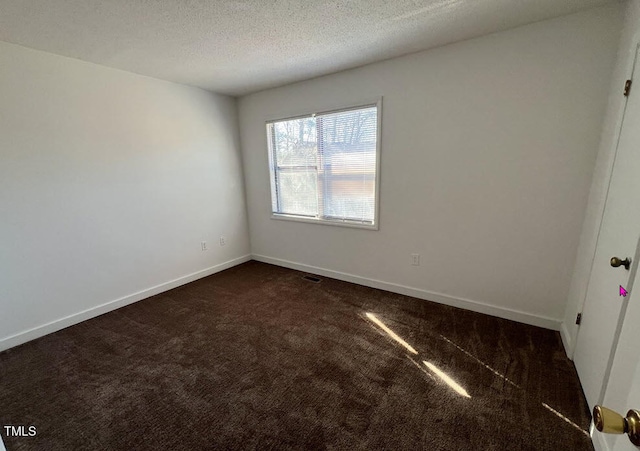 unfurnished room featuring dark carpet, a textured ceiling, and baseboards
