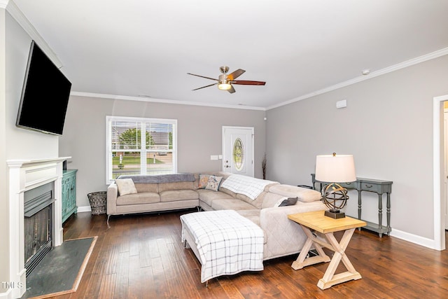 living room with ceiling fan, crown molding, dark wood-style flooring, baseboards, and a fireplace with raised hearth