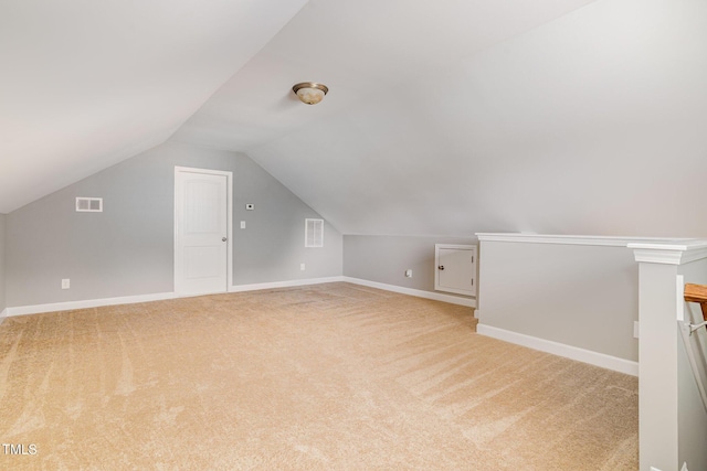 bonus room featuring light colored carpet, vaulted ceiling, and baseboards