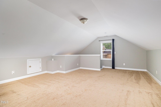 additional living space with lofted ceiling, light carpet, and baseboards