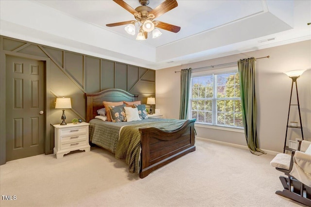 bedroom with light carpet, baseboards, a tray ceiling, ceiling fan, and crown molding
