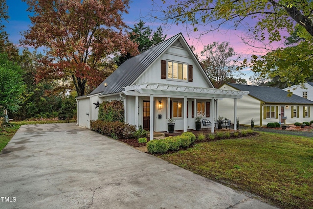 modern inspired farmhouse with a pergola, a standing seam roof, metal roof, board and batten siding, and a lawn
