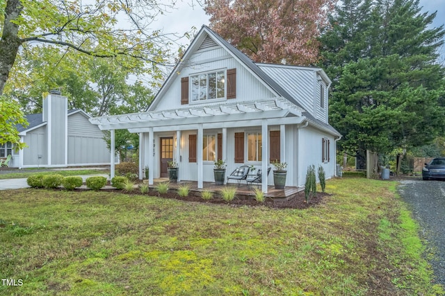modern farmhouse style home featuring a porch, a front lawn, a standing seam roof, and metal roof