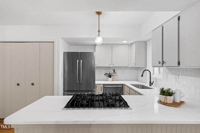 kitchen featuring stainless steel appliances, a sink, tasteful backsplash, a peninsula, and pendant lighting