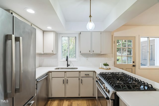 kitchen with stainless steel appliances, a sink, light countertops, and recessed lighting