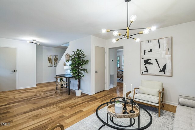 living area featuring wood finished floors, a chandelier, and baseboards